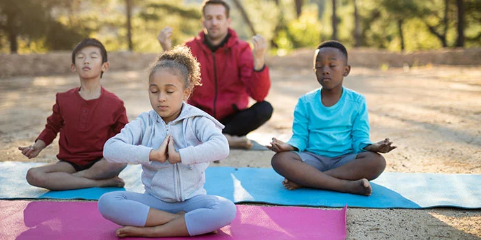 Meditating kids coach and kids meditating in park